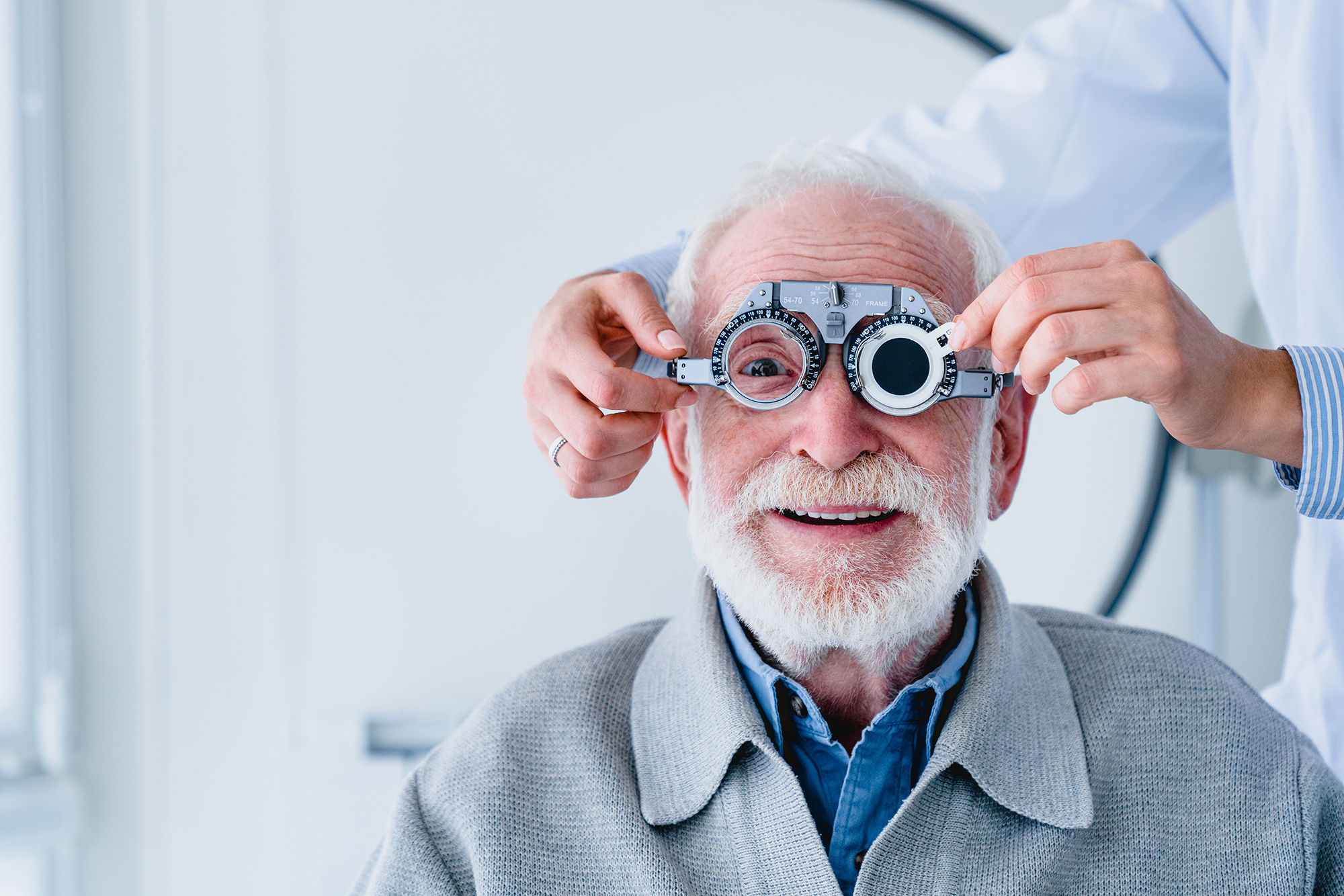 Portrait of a mature man fitting ophthalmic spectacles with doctor`s help
